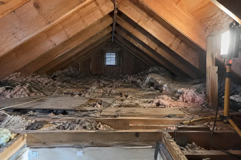 Attic before reconditioning: thin insulation and a crushed duct