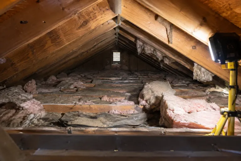 Before: Old batts sagging and torn, several lying on the ground on a torn vapor barrier