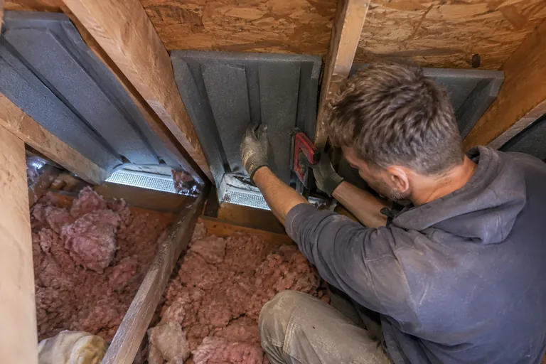 Foam baffles stapled between rafters at the eaves above the soffit vents
