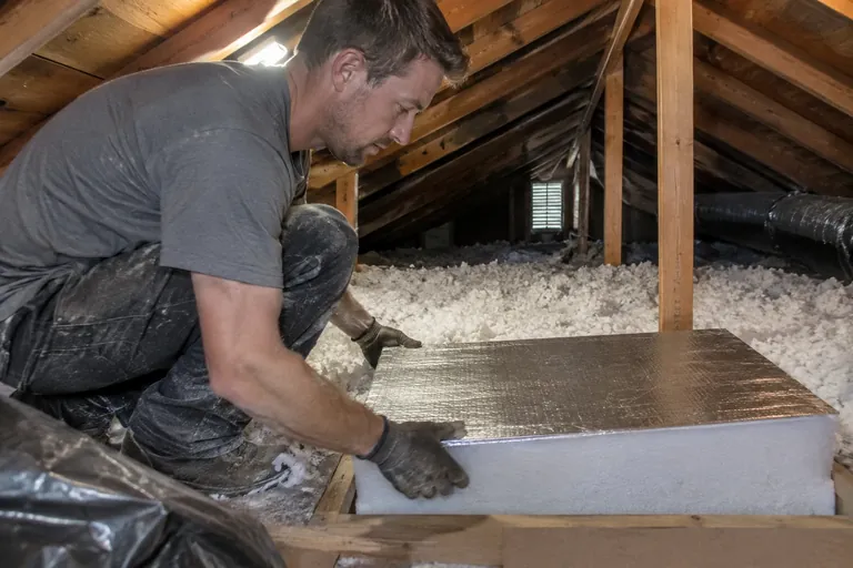 Finished attic with a deep, even layer of blown insulation and an insulated hatch cover